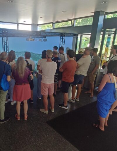 Gruppe von Menschen steht vor einer Leinwand mit 3D-Modell im hellen Stadthausfoyer mit grossen Fenstern in Kloten.